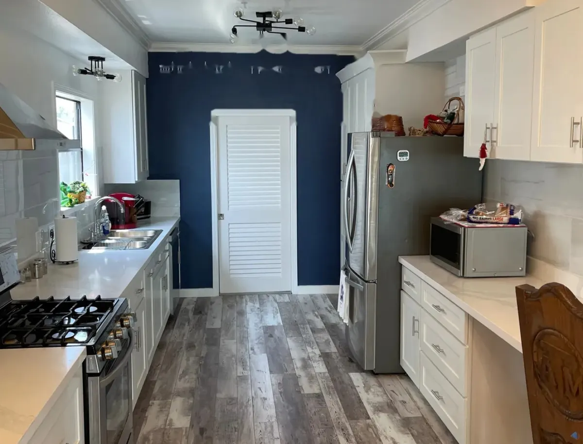 Completed MSS kitchen renovation with white cabinets, stone counters, and a navy accent wall